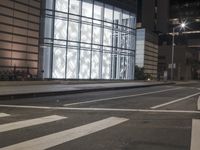 a building has a glass front in a city street, with greenery in front