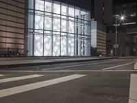 a building has a glass front in a city street, with greenery in front