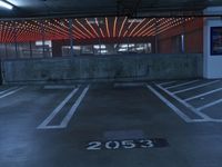 a parking garage filled with empty areas and red lights as a wall in the background