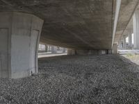 under an overpass on a freeway with rocks underneath it, with the road going underneath the bridge