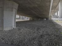 under an overpass on a freeway with rocks underneath it, with the road going underneath the bridge