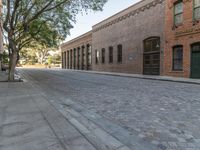 an empty street with lots of brickwork and trees on either side of the road