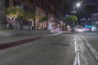 an urban street scene at night with no one on the sidewalk or sidewalk curb lighting