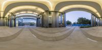 360 - view of building with metal pillars inside at night time by a man walking in an open space