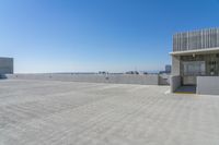 a building on the ground in front of a city skyline and the ocean view, showing its concrete facade