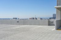 a building on the ground in front of a city skyline and the ocean view, showing its concrete facade