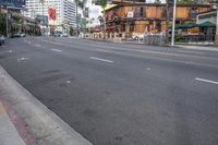 an empty road with no cars and a few tall buildings behind it with palm trees in the background