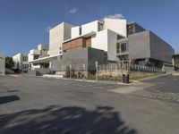 a modern office building with gray blocks surrounding it and cars parked in the parking lot