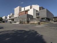 a modern office building with gray blocks surrounding it and cars parked in the parking lot