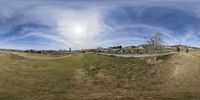 a fish eye view of some buildings on the side of the road and a fence in front of the grass