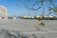 an empty parking lot with buildings in the background and leaves in the middle of it