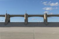 an empty concrete wall with a bridge on top and one with a bike rack in the foreground