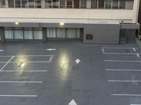 an empty parking lot with multiple lines on the floor and several windows on one side and arrows pointing up at left side