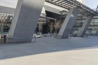 a walkway near an office building is shown, with steel poles in the middle and concrete panels that form the ceiling