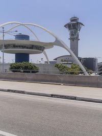 traffic moves down the freeway near an airport control tower and air traffic clock with other buildings in the background