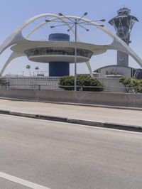 traffic moves down the freeway near an airport control tower and air traffic clock with other buildings in the background