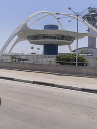 traffic moves down the freeway near an airport control tower and air traffic clock with other buildings in the background