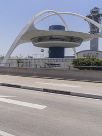 traffic moves down the freeway near an airport control tower and air traffic clock with other buildings in the background