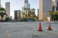 a parking lot surrounded by some tall buildings with graffiti on the top of it and orange traffic cones sitting next to them