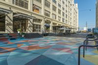 a multi - colored floor in a street with multiple levels in the center and lots of people walking down it