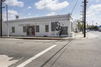 a painting of a man that has just completed a mural on a building is painted by a street corner artist