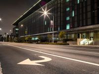 a white arrow symbol on the street with buildings and night sky in the background of this photo