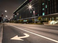 a white arrow symbol on the street with buildings and night sky in the background of this photo