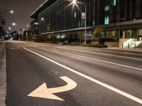 a white arrow symbol on the street with buildings and night sky in the background of this photo