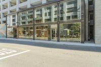 an office building is reflected in a glass wall on the street corner in downtown vancouver