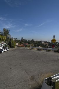 two police cars parked next to a road under an overpass with palm trees and houses in the distance