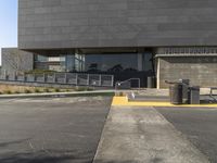 a person standing next to a parking lot near some stairs and tables outside the building