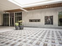 a tiled floor outside of a building near pots of planties on each side of the room