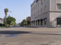 the view along a city street showing a building and a few cars on it and the street light