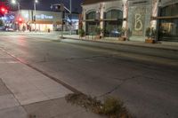 the city street has several lights lit up on it's sides as well as a tree near a curb