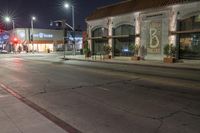 the city street has several lights lit up on it's sides as well as a tree near a curb