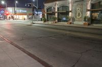 the city street has several lights lit up on it's sides as well as a tree near a curb