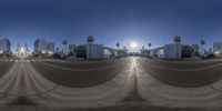 a street view of buildings and palm trees at sunset or sunrise, from a fish - eye lens