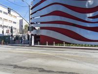 a large american flag in front of some tall buildings and other office structures with a crosswalk in the foreground