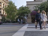 two people crossing the street in front of a building at an intersection in downtown san francisco