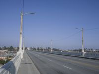 a deserted bridge on the side of the highway with electric power lines above them and the horizon in the distance