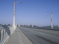 a deserted bridge on the side of the highway with electric power lines above them and the horizon in the distance