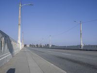 a deserted bridge on the side of the highway with electric power lines above them and the horizon in the distance