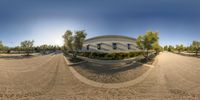 a fisheye lens shot of a skate park with an athletic center building on the left, and a tennis court in the middle of it