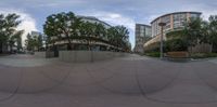 a large empty plaza with three buildings and some trees next to it with trees and plants in it