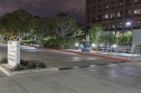 an empty parking lot lit up at night with lights on and trees in the background