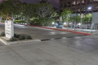 an empty parking lot lit up at night with lights on and trees in the background