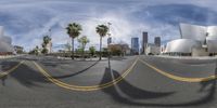 view of buildings from a road at a city intersection with palm trees and blue sky