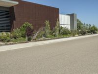 a city street with a building in the background with trees lining it and a few bushes along the side of the road