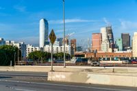 several barrels lined up on a roadway next to the city skyline and road with traffic