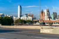 several barrels lined up on a roadway next to the city skyline and road with traffic